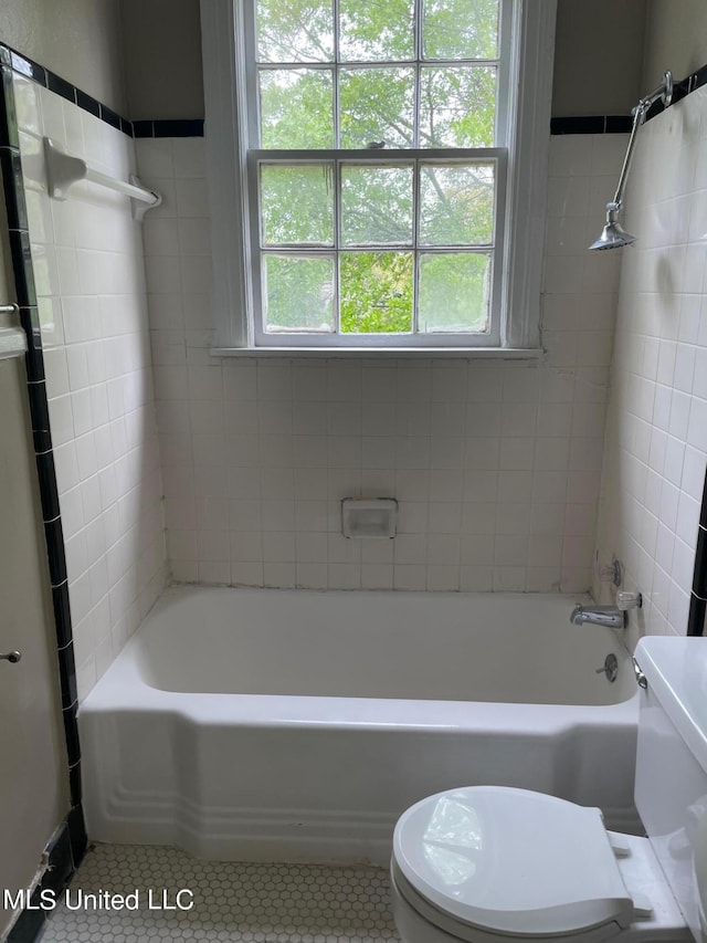 bathroom with toilet, tiled shower / bath combo, and tile patterned floors