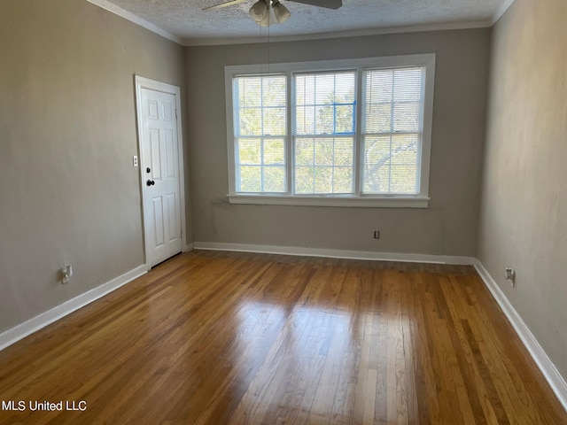 empty room featuring a textured ceiling, ceiling fan, crown molding, and hardwood / wood-style floors