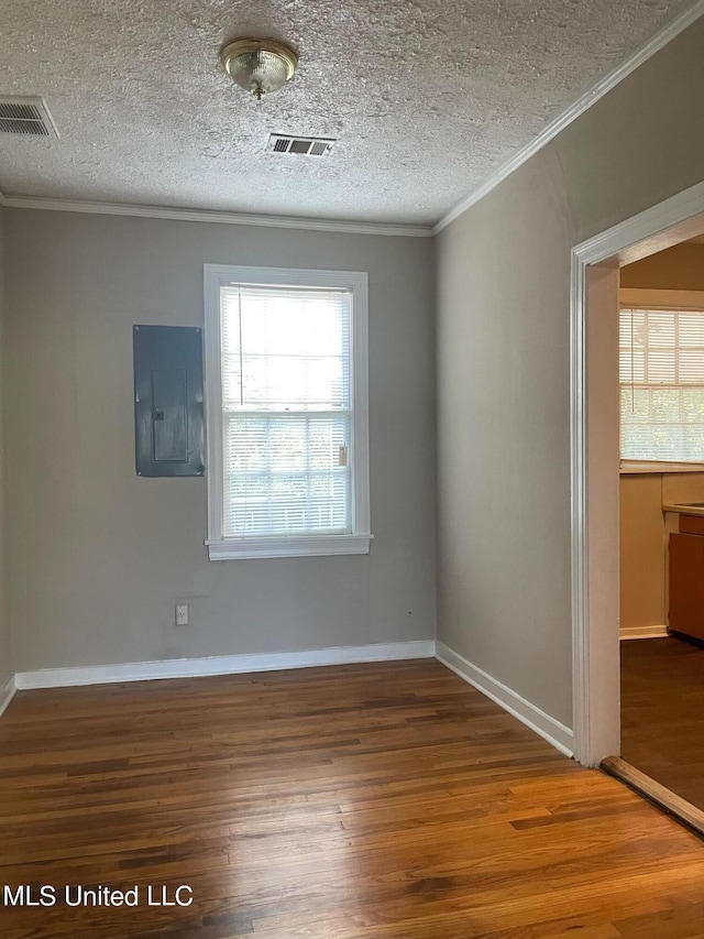 spare room with electric panel, ornamental molding, and wood-type flooring