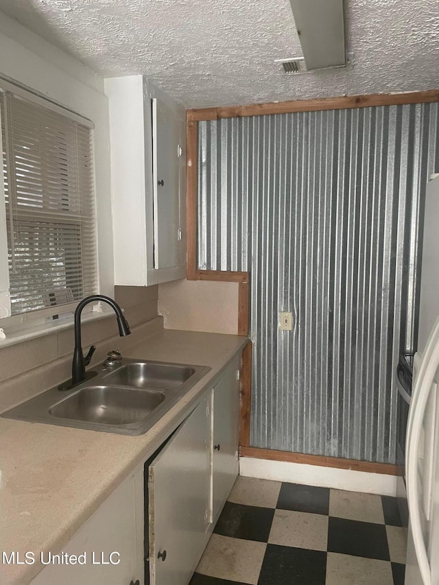 kitchen with a textured ceiling, fridge, and sink