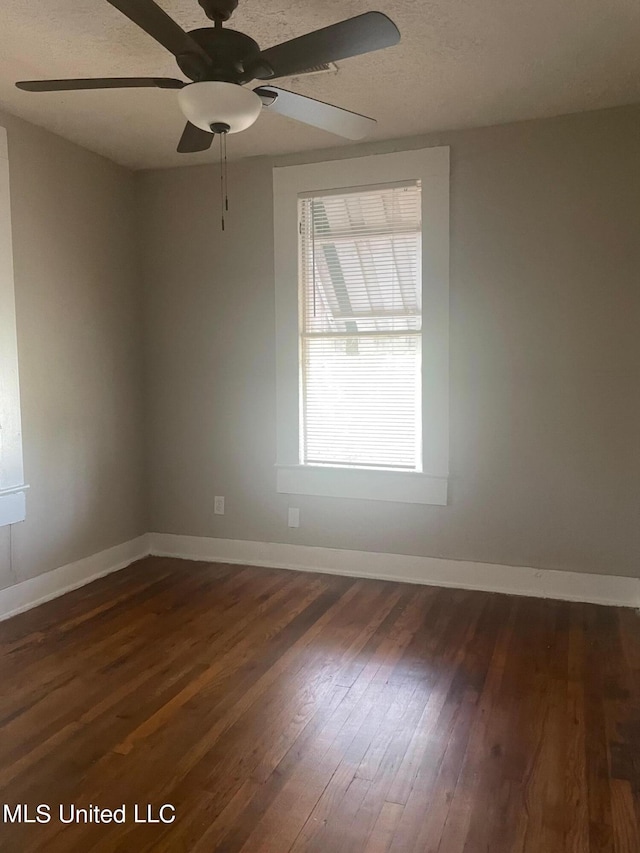 spare room with ceiling fan, a wealth of natural light, and dark hardwood / wood-style floors