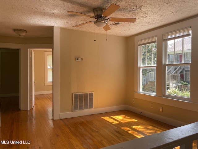 empty room featuring a textured ceiling, ceiling fan, and wood-type flooring