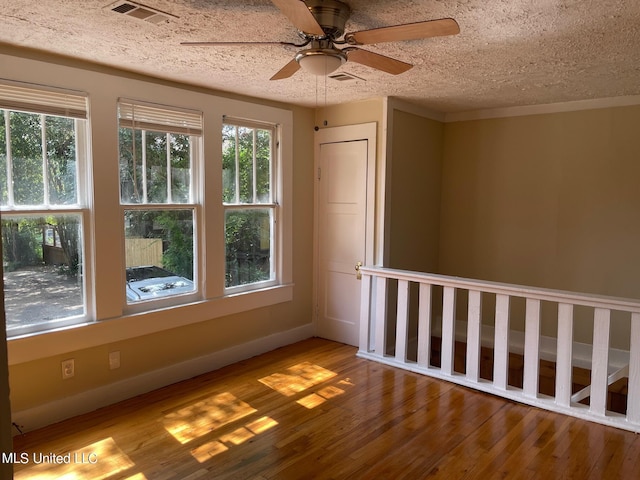 spare room featuring a textured ceiling, ceiling fan, a healthy amount of sunlight, and light hardwood / wood-style flooring