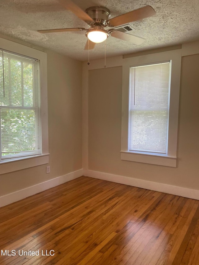 empty room featuring a textured ceiling, ceiling fan, and wood-type flooring