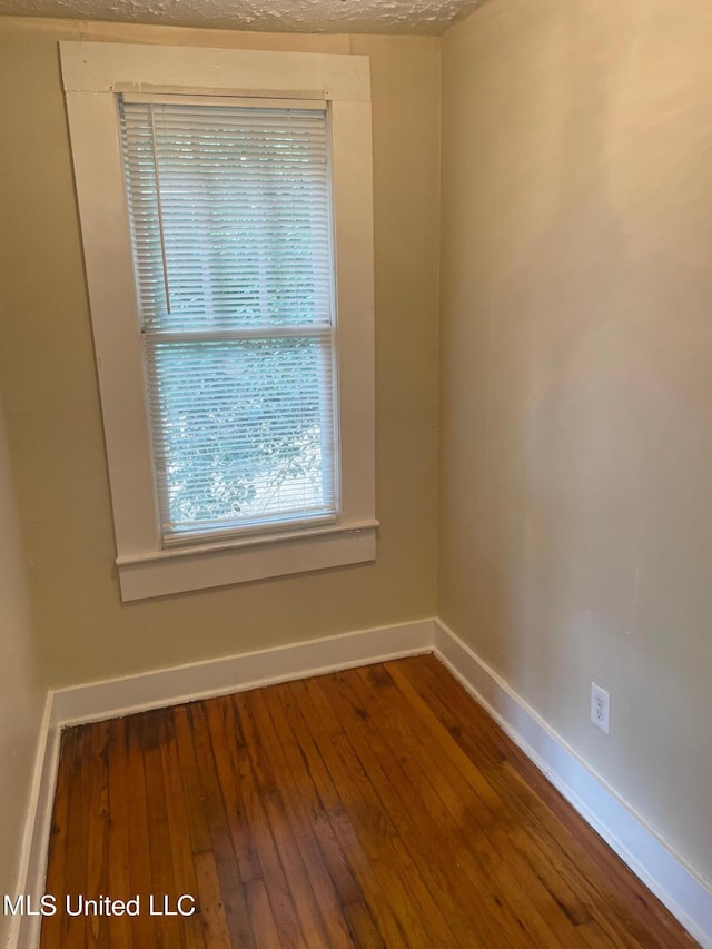 empty room with hardwood / wood-style floors and a textured ceiling