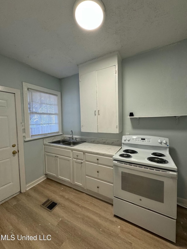 kitchen with a textured ceiling, white cabinets, white electric stove, light hardwood / wood-style floors, and sink