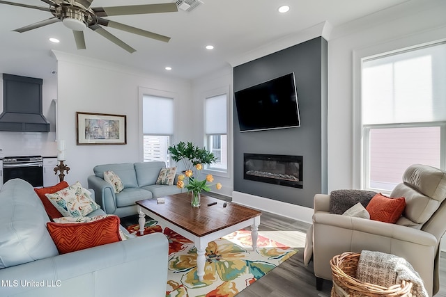 living room with a wealth of natural light, ceiling fan, crown molding, and hardwood / wood-style flooring