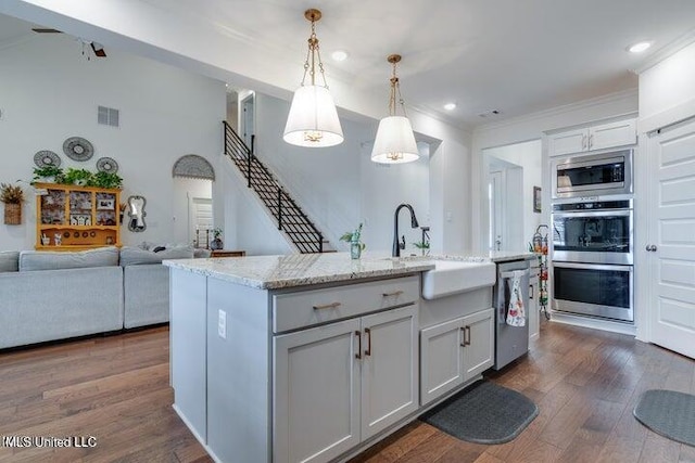 kitchen with visible vents, dark wood-type flooring, light stone countertops, appliances with stainless steel finishes, and hanging light fixtures