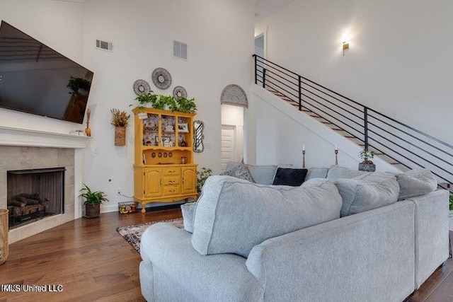 living area featuring dark wood-type flooring, stairway, visible vents, and a towering ceiling