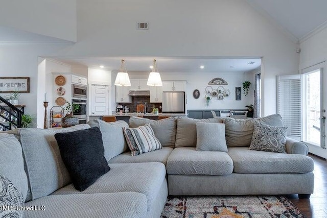 living area featuring crown molding, wood finished floors, visible vents, and high vaulted ceiling