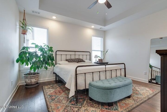 bedroom featuring a tray ceiling, baseboards, visible vents, and hardwood / wood-style flooring