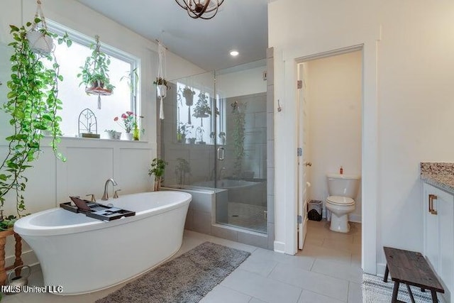 bathroom featuring tile patterned floors, a freestanding tub, toilet, a shower stall, and vanity