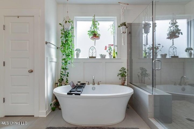 bathroom featuring tile patterned floors, a soaking tub, a stall shower, and a decorative wall