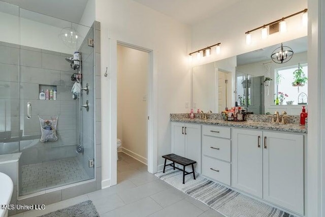 bathroom featuring double vanity, a stall shower, a sink, tile patterned floors, and toilet