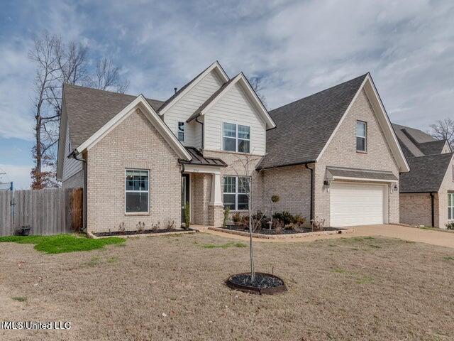 craftsman-style home with brick siding, concrete driveway, a front lawn, and fence