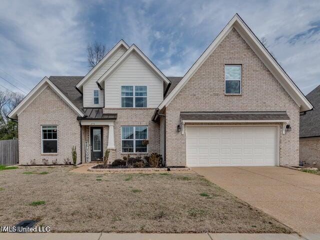 view of front of home with fence, brick siding, driveway, and metal roof