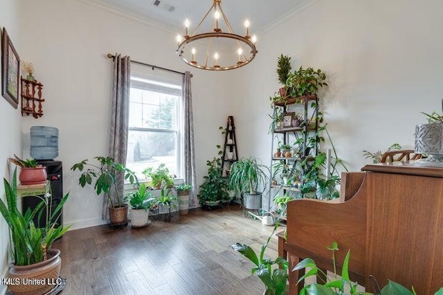 living area with a notable chandelier, wood finished floors, baseboards, and ornamental molding