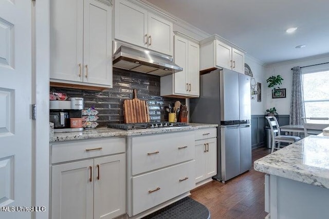 kitchen featuring dark wood-type flooring, under cabinet range hood, ornamental molding, appliances with stainless steel finishes, and white cabinets