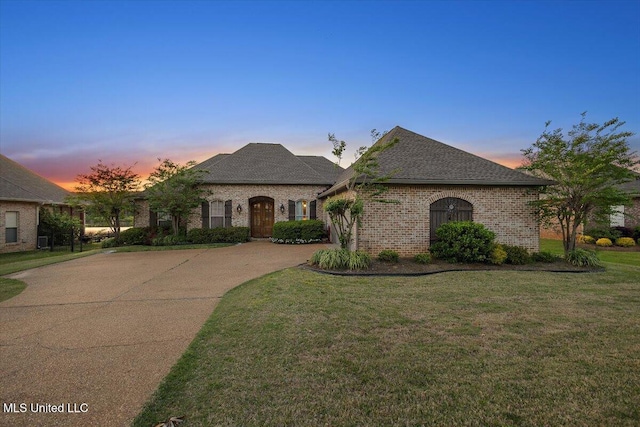 136 Mullherrin Dr, Madison, MS 39110 - french country style house with a shingled roof, concrete driveway, a front yard, and brick siding