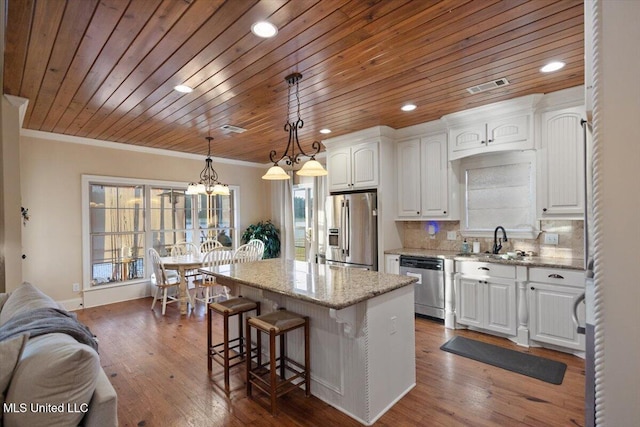 136 Mullherrin Dr, Madison, MS 39110 - kitchen featuring a breakfast bar, ornamental molding, white cabinetry, a kitchen island, and stainless steel appliances