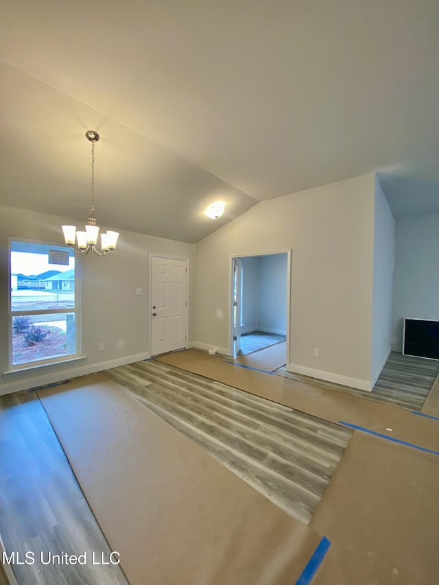 unfurnished living room with wood-type flooring, an inviting chandelier, and lofted ceiling