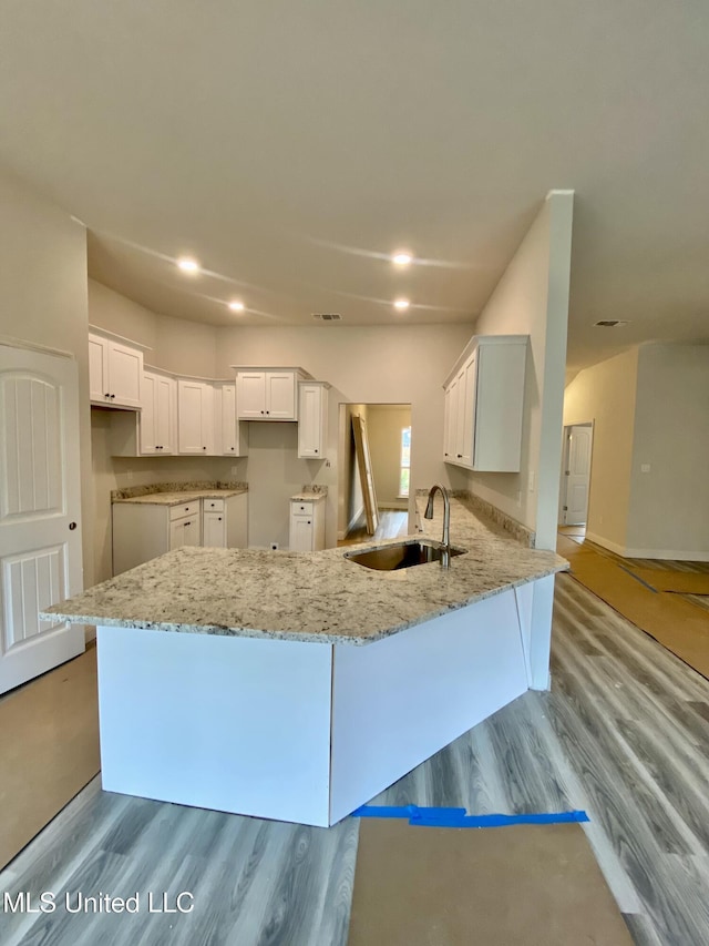 kitchen featuring kitchen peninsula, white cabinetry, light stone countertops, and sink