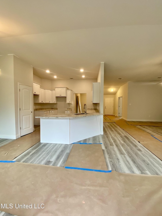 kitchen with kitchen peninsula, light hardwood / wood-style floors, white cabinetry, and sink