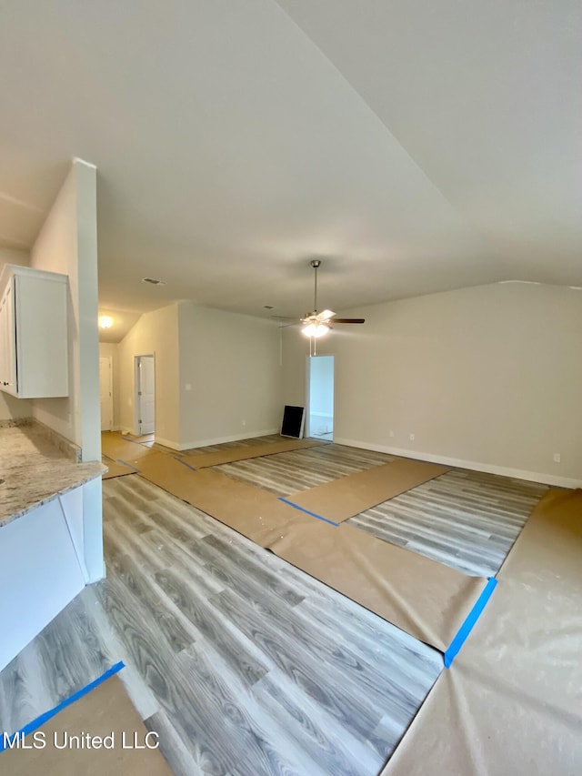 unfurnished living room with light wood-type flooring, vaulted ceiling, and ceiling fan