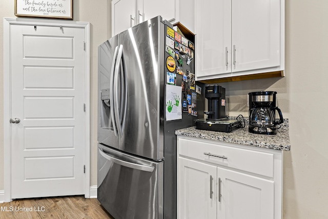 kitchen with white cabinets, light stone countertops, wood finished floors, and stainless steel fridge with ice dispenser