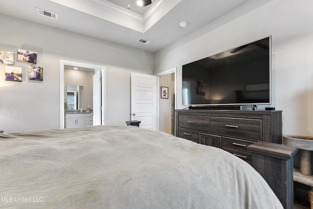 bedroom featuring visible vents, connected bathroom, a tray ceiling, and ornamental molding