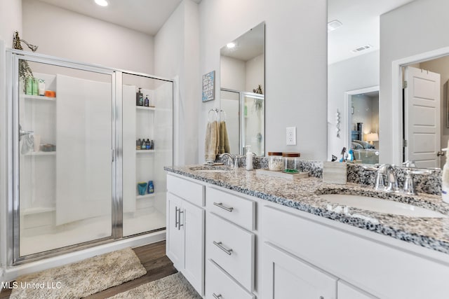 bathroom featuring a sink, visible vents, wood finished floors, and a stall shower