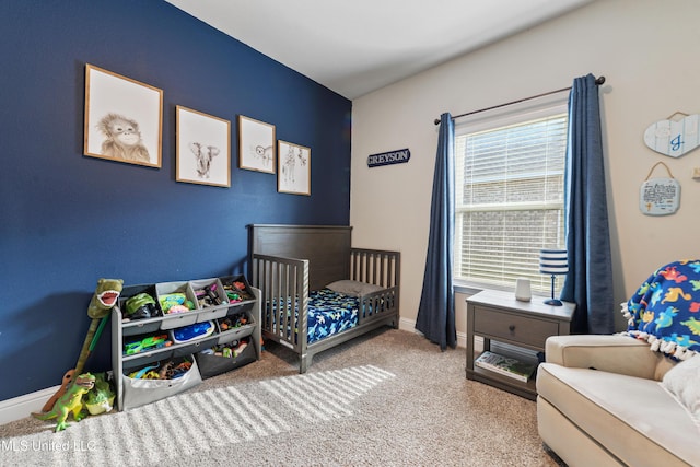 bedroom with a crib, baseboards, and carpet floors