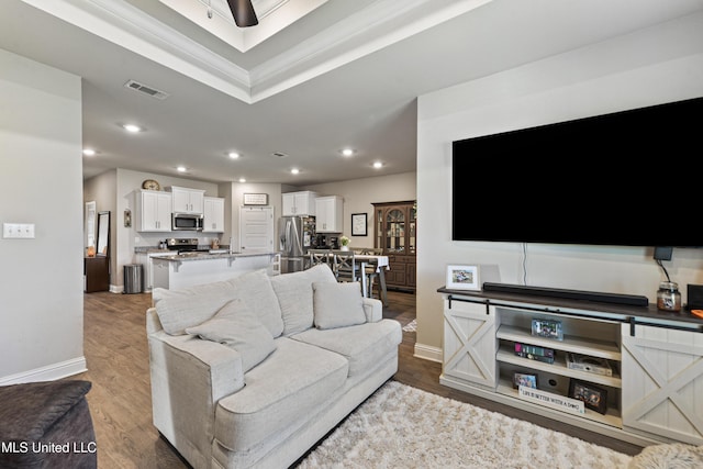 living room with visible vents, wood finished floors, recessed lighting, crown molding, and baseboards