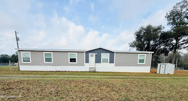 manufactured / mobile home featuring an outbuilding, fence, a storage shed, and a front yard