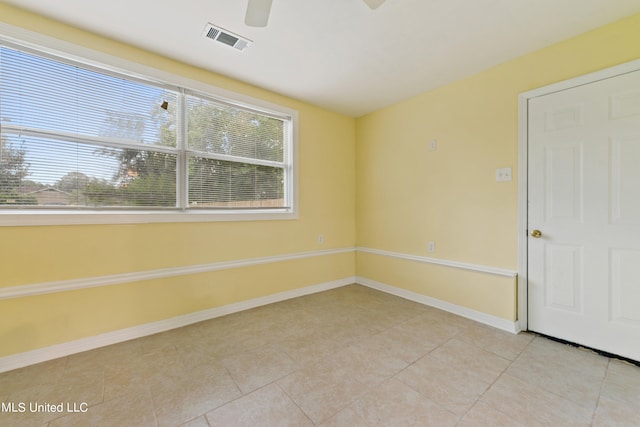 empty room featuring a wealth of natural light, ceiling fan, and light tile patterned floors