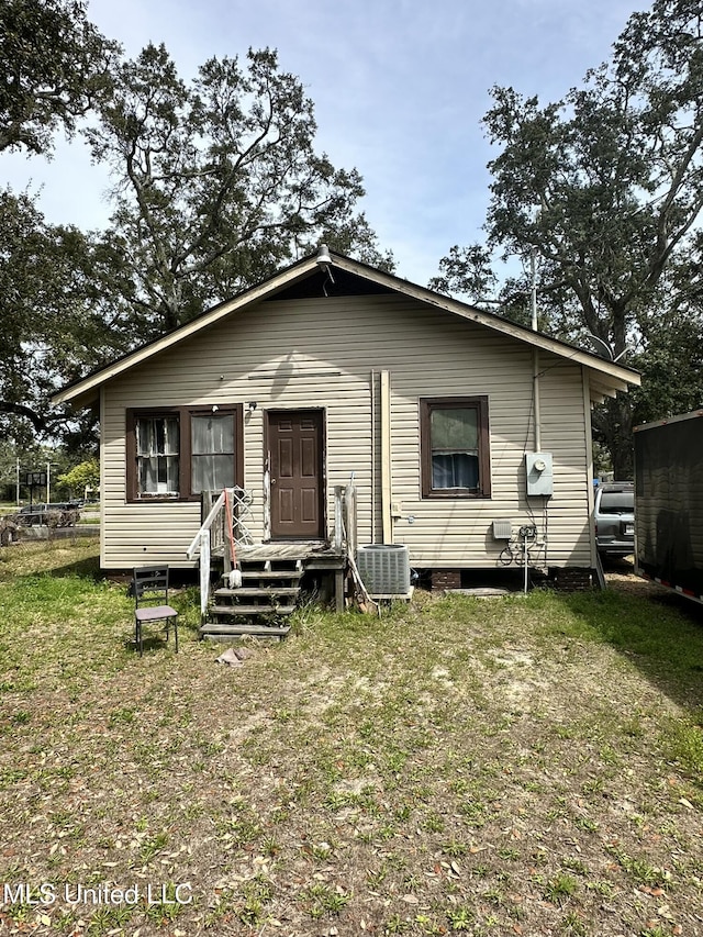 rear view of house with central AC unit and a lawn