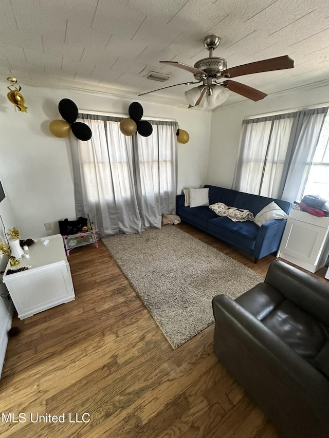 living area with visible vents, a textured ceiling, wood finished floors, and a ceiling fan