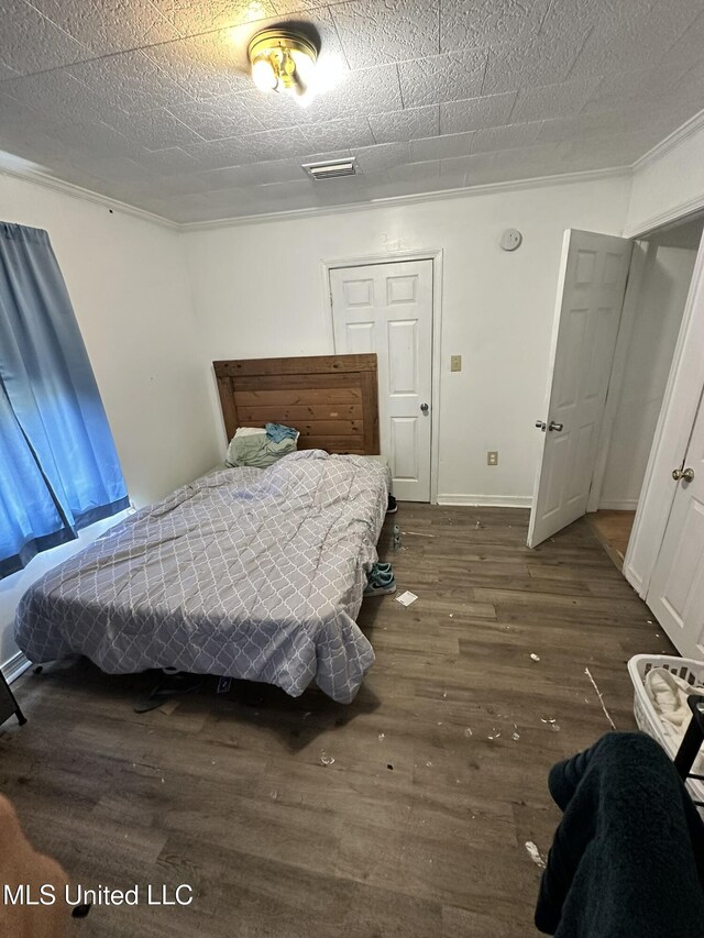 bedroom with baseboards, visible vents, and wood finished floors