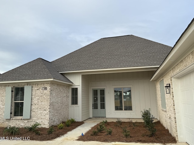 138 Coventry Ln, Canton, MS 39046 - property entrance featuring a shingled roof, brick siding, a garage, and board and batten siding