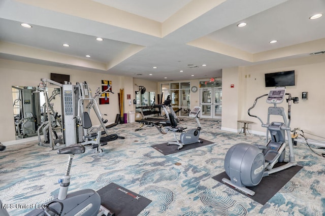 gym featuring a tray ceiling and carpet flooring