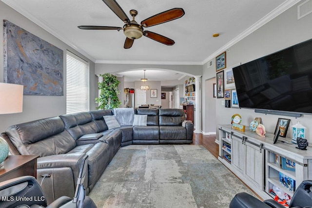 living room with decorative columns, a ceiling fan, crown molding, arched walkways, and wood finished floors