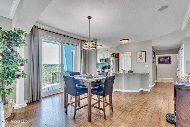 dining area with baseboards, ornamental molding, and light wood finished floors