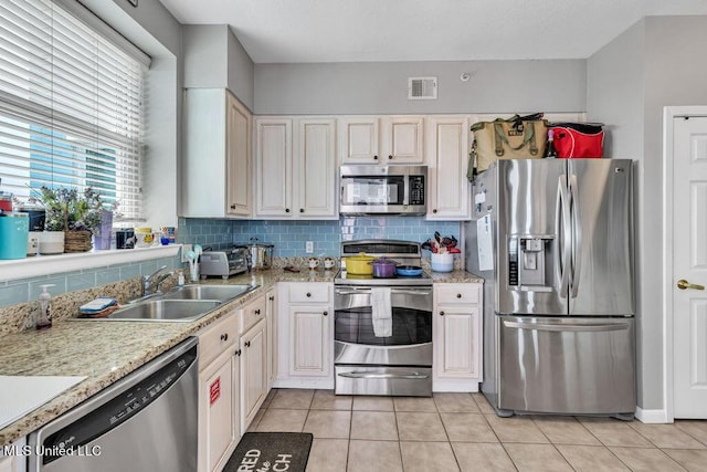 kitchen with a sink, stainless steel appliances, light tile patterned floors, tasteful backsplash, and visible vents