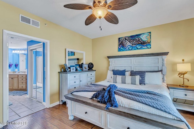 bedroom featuring ensuite bath, a ceiling fan, visible vents, and light wood-type flooring