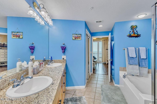 ensuite bathroom featuring visible vents, a sink, a textured ceiling, and tile patterned floors