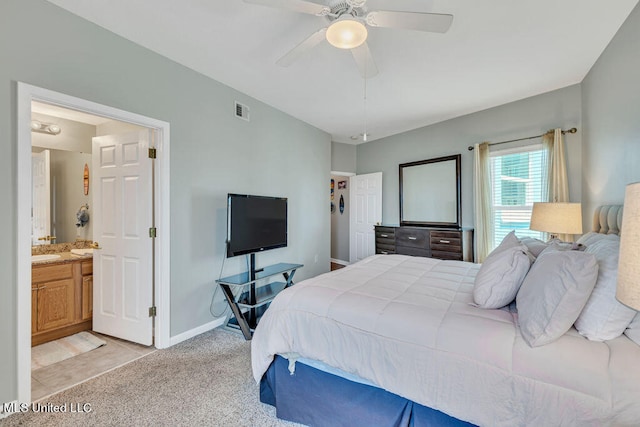 bedroom featuring ensuite bathroom, light colored carpet, sink, and ceiling fan