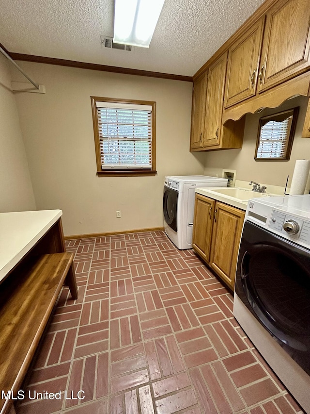 502 Frederick Dr, Cleveland, MS 38732 - laundry area with cabinet space, washing machine and dryer, brick patterned floors, a textured ceiling, and baseboards