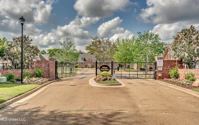 603 Charmant Pl, Ridgeland, MS 39157 - view of asphalt road with a gate, a gated entry, curbs, and street lighting