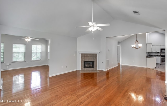 603 Charmant Pl, Ridgeland, MS 39157 - unfurnished living room with ceiling fan, a chandelier, high vaulted ceiling, a tiled fireplace, and light wood finished floors