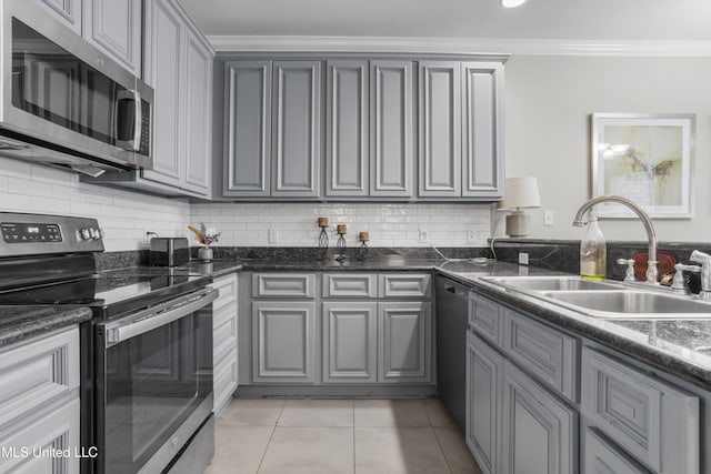 kitchen with light tile patterned flooring, sink, crown molding, dark stone countertops, and stainless steel appliances